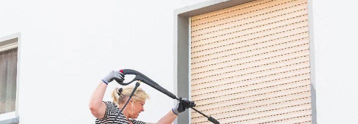 Person reinigt Fassade mit Hochdruckreiniger